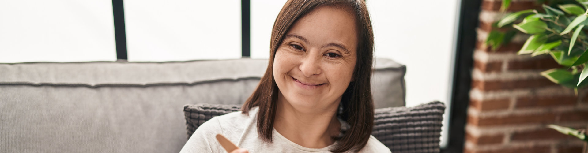 smiling woman with down syndrome sitting in the sofa